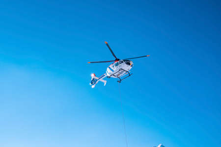 Police helicopter flying above against blue sky on sunny dayの写真素材