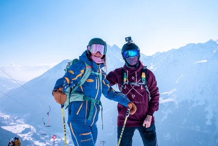 Snowboarder and skier standing against beautiful mountains at winter resortの写真素材