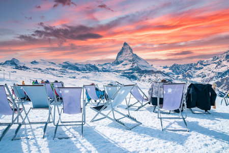 Tourist enjoying view of Matterhorn while sitting on chairs during sunsetの写真素材