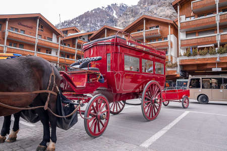 Red horsecart on street against houses in townsquare with mountain in backgroundの写真素材