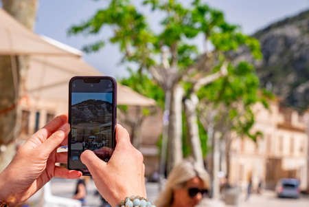 Cropped image of man photographing through mobile phone in city