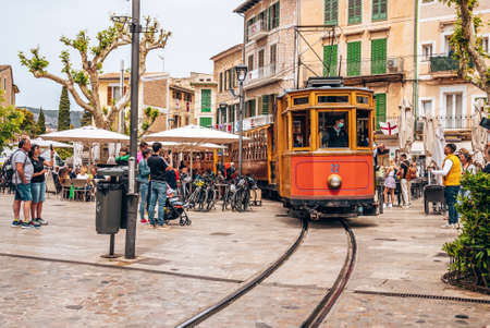 Tourists looking at famous tram moving on rail tracks against buildings in city