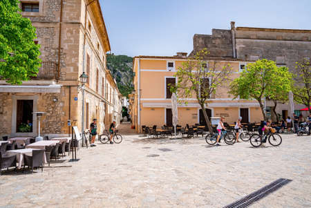 Tourists cycling on street against buildings in city during sunny dayの写真素材