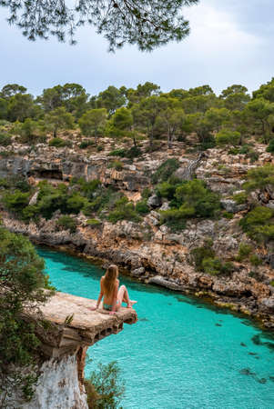 Thoughtful female tourist relaxing on broken bridge while looking at seaの写真素材