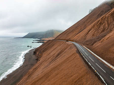 Endless road into the cloudy mountains and hills of Iceland during sunny cloudy weather.の写真素材