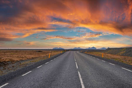 Diminishing empty road amidst volcanic landscape against cloudy sky during sunsetの写真素材