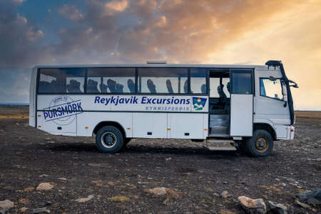 Empty Reykjavik Excursions bus parked on lava sand against sky during sunsetの写真素材