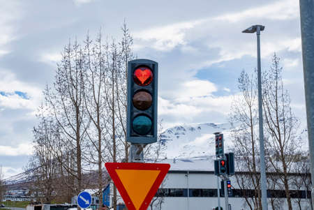 Creative heart shaped stop light in traffic signal at city against sky
