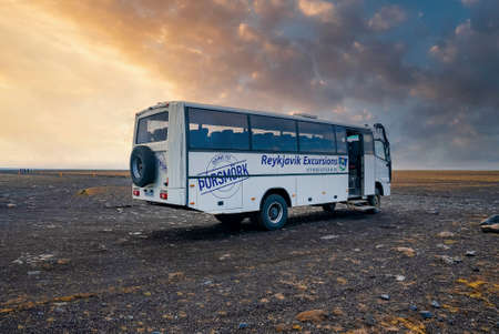 Reykjavik Excursions flybus parked on lava sand against cloudy sky during sunsetの写真素材