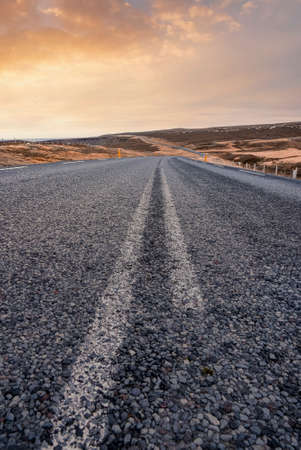 Diminishing empty road amidst landscape in volcanic valley against sky during sunsetの写真素材