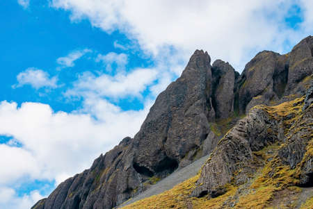 Low angle view of rock formations on volcanic landscape against blue sky