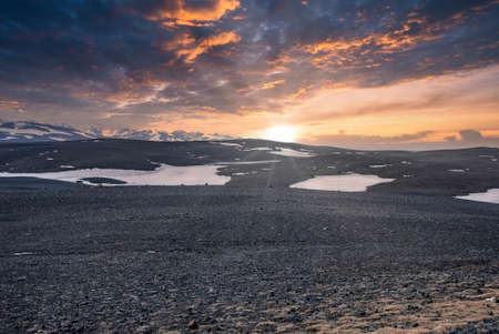 Scenic view of sun shining over snow on volcanic landscape during sunsetの写真素材