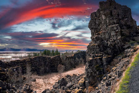 View of rock formations and trees by lakes on volcanic landscape during sunset
