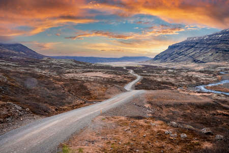 View of road amidst volcanic landscape at Eastfjords against dramatic skyの写真素材