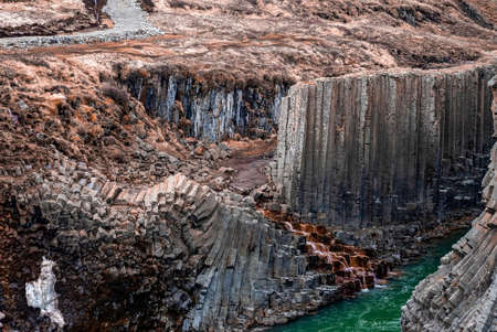 Scenic view of stream flowing amidst basalt columns formation at Eastfjords