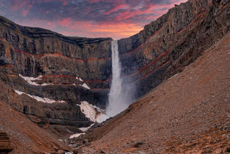 Beautiful cascades of Hengifoss falling from mountains against dramatic sky