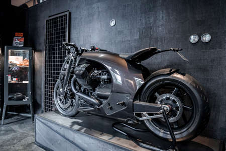 Modern motorcycle on platform against gray wall by rack in One sixty smokehouseの写真素材