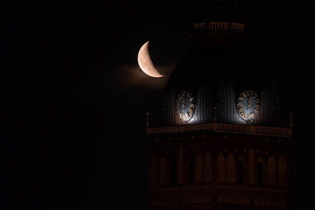 Beautiful quarter moon over Riga old town behind Domes cathedral clock.の写真素材