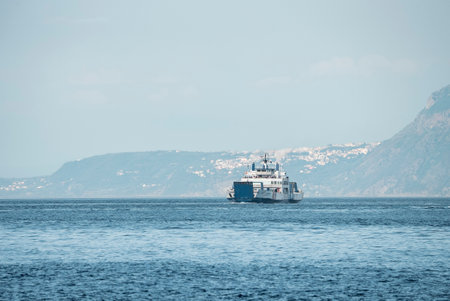 Ship moving on sea against mountain with blue sky in backgroundの写真素材