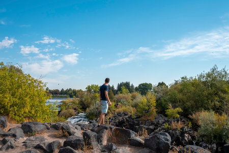 Traveler at beautiful Idaho waterfalls while standing on rock during summerの写真素材