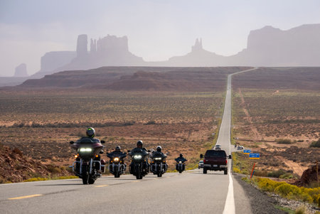 Tourists riding motorcycles on highway at Monument Valley Park in summer