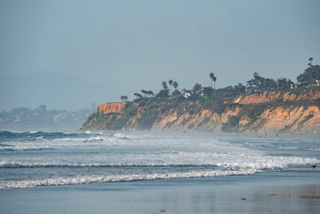 Scenic view of waves splashing in sea by rocky cliff at San Diegoの写真素材