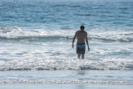 Shirtless man standing amidst waves splashing in sea during vacation
