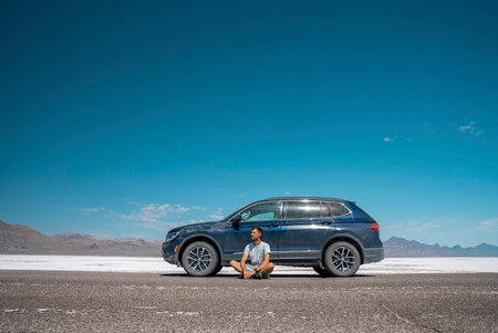 Tourist relaxing by car at Bonneville salt flat with sky in background