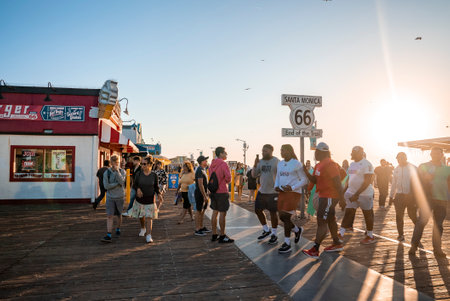 People walking by Santa Monica 66 end of the trail sign on pier at sunsetの写真素材