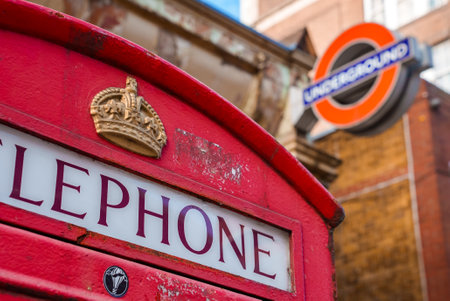 Typical London telephone booth on a rainy day and a beautiful subway station in the background.の写真素材