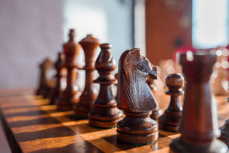 Closeup of brown chess pieces arranged on chessboard in hotel roomの写真素材