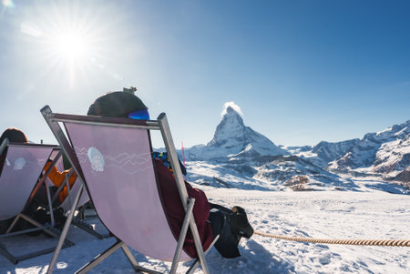 Young snowboarder cheering with a beer after skiing day in a bar or a cafe at the Zermatt ski resortの写真素材