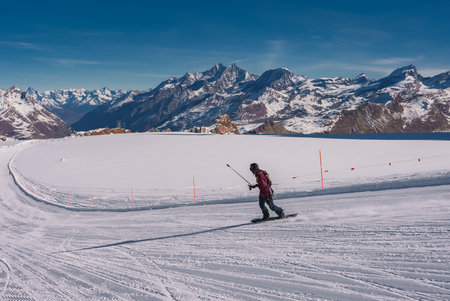 Young man snowboarding in Zermatt ski resort right next to the famous Matterhorn peak.の写真素材