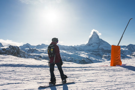 Young man snowboarding in Zermatt ski resort right next to the famous Matterhorn peak.の写真素材