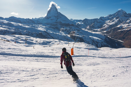 Young man snowboarding in Zermatt ski resort right next to the famous Matterhorn peak.の写真素材