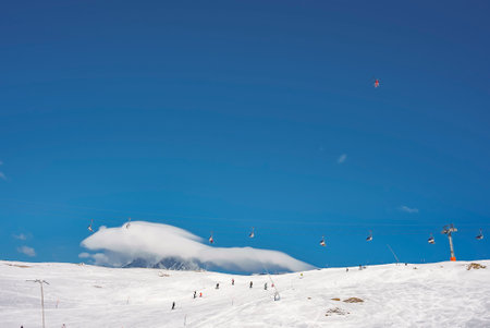 Skiers skiing on slopes and ski chair lifts over snowy mountainの写真素材