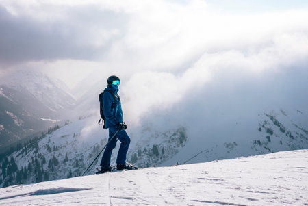 Tourist with ski on peak of snow covered mountain during vacationの写真素材