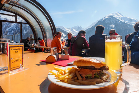 Burger with beer glass on table at ski resort on sunny dayの写真素材