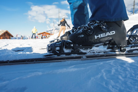 Low section of skier wearing boots and ski on snow covered slopeの写真素材