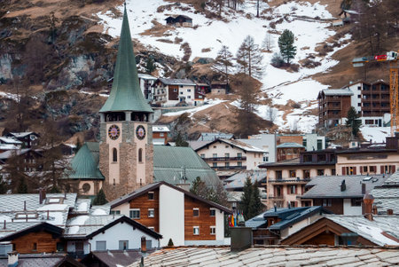 Clock tower amidst buildings with snow mountain in backgroundの写真素材
