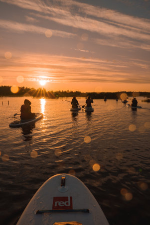 Stand up paddle boarding or standup paddleboarding on quiet lake at sunrise