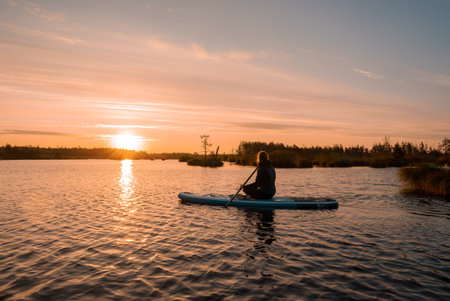 Stand up paddle boarding or standup paddleboarding on quiet lake at sunriseの写真素材