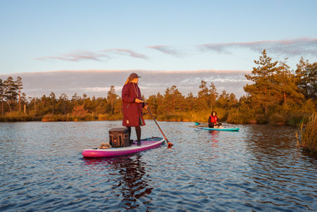 Stand up paddle boarding or standup paddleboarding on quiet lake at sunrise