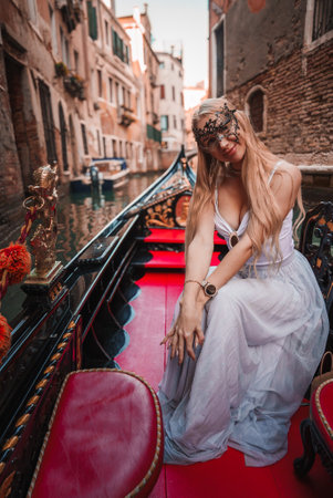 Serene Woman in White Dress Sitting on Gondola in Venice Canal, Italyの写真素材