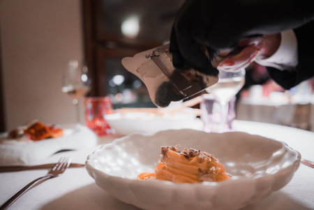 Elegant dining experience in Venice: Person using spoon to serve pasta onto white plate.の写真素材