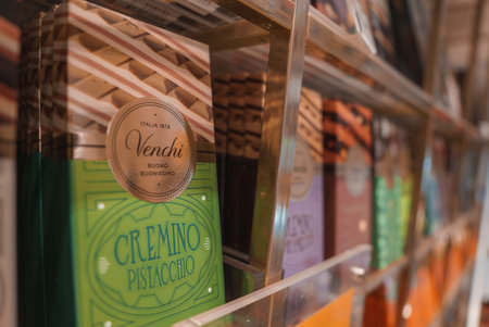 A side angle view of a well-organized display of various chocolate bars in a glass case at a store....