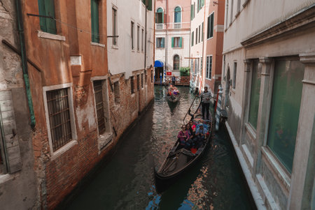 A serene gondola glides down a narrow canal in Venice, Italy, capturing the timeless beauty and romance of the city's iconic charm.の写真素材