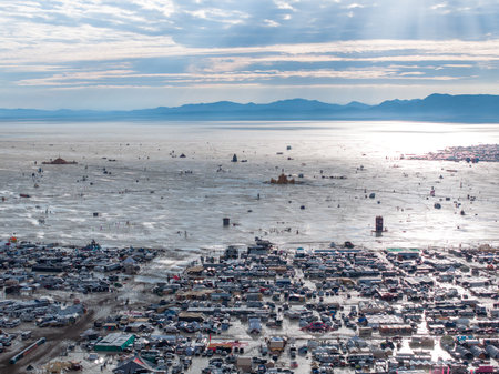 Aerial shot of a city landscape with mountains in the background under a cloudy sky.の写真素材