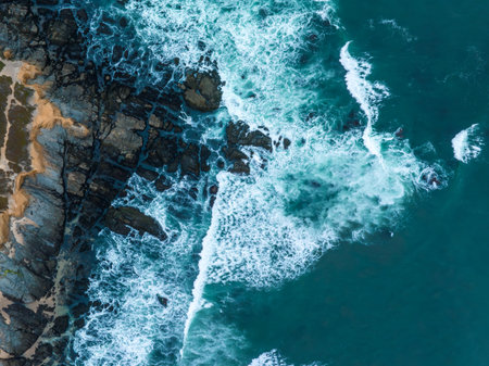 Aerial view of ocean waves crashing against rocky coastlineの写真素材