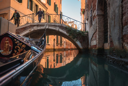 Classic Black Gondola Steered by Gondolier on Serene Venice Canal - Charming Italian Sceneの写真素材